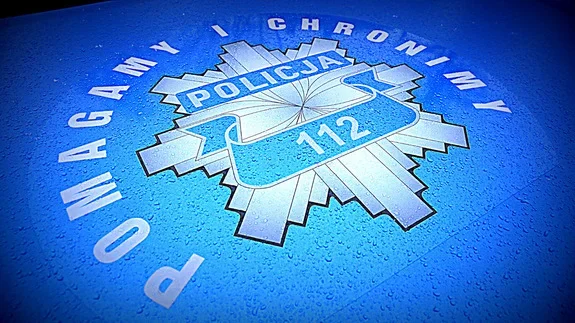 Niebieskie logo Policji z numerem alarmowym 112 i hasłem „Pomagamy i chronimy” na powierzchni z kroplami wody.