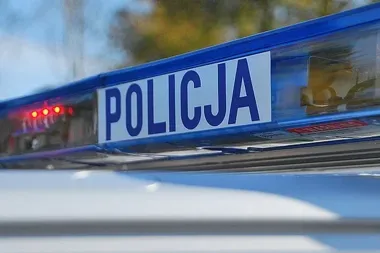 Fragment niebieskiego lightbaru oznaczonego napisem POLICJA na dachu policyjnego pojazdu.