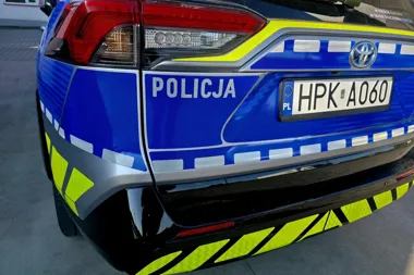 Tył oznakowanego radiowozu policji z napisem POLICJA i tablicą rejestracyjną HPK A060 stoi na asfaltowej nawierzchni.