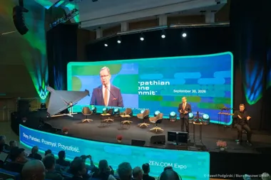Mężczyzna w garniturze przemawia na scenie podczas konferencji przed publicznością, na ekranie wyświetlana jest jego powiększona postać oraz napis „Carpathian D